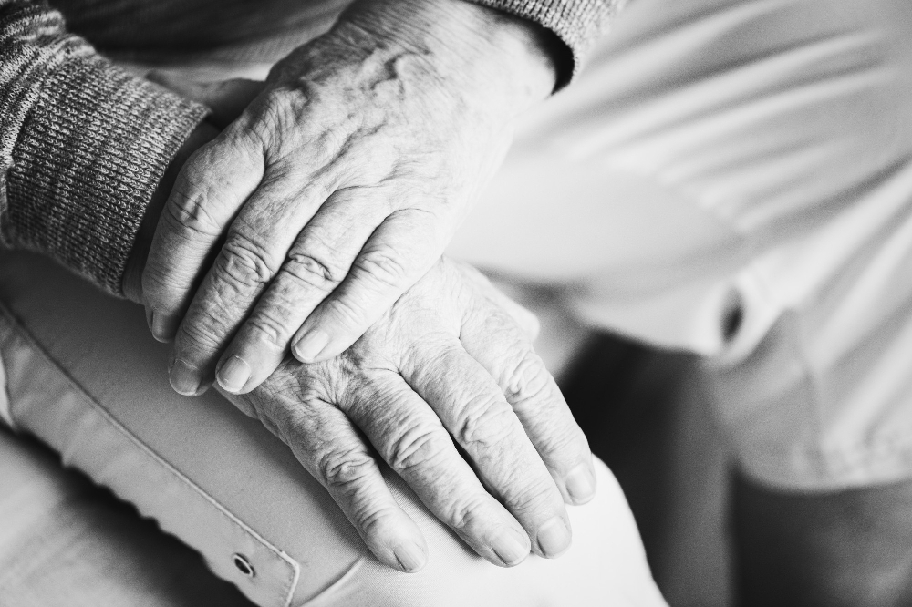 Close-up of an elderly person's hands resting together while seated.